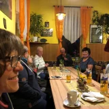 Gespräche im Gasthaus „Zur Linde“  Angeregt sprechen die Menschen an einem langen Gasthaustisch miteinander Kirchengemeinde Lichtentanne
