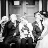 Schnappschuß bei einer Hochzeit Auf einer Bank sitzen zwei ältere Damen und Herren und lachen herzhaft. Daneben hat der Bräutigam seine Braut auf dem Schoß. Sie küsst ihn. 2016